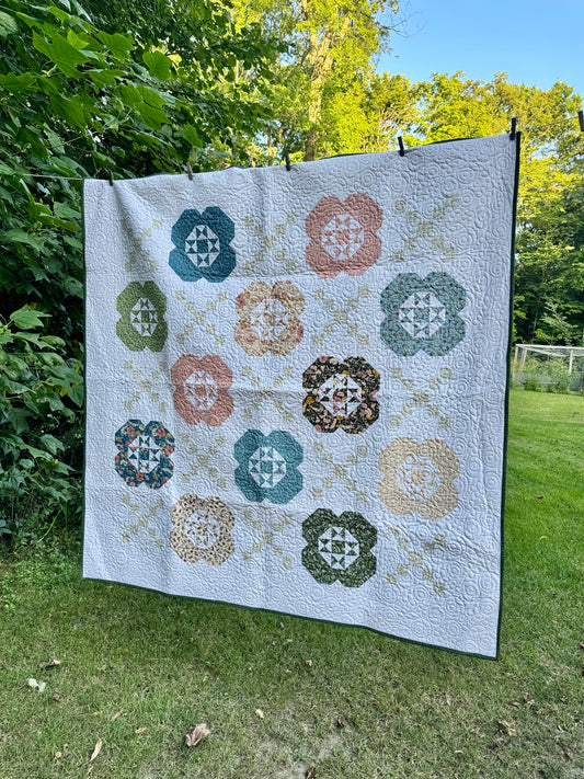 Gardenia Quilt hanging outside. Features 12 flower blocks and 13 Irish chain blocks alternating. Made using Petalush fabrics.