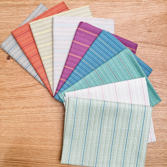 Nine Quiltessential Minis stripe fat quarters by Laundry Basket Quilts, fanned out to show the fabrics.