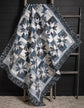 Blue, black, and white quilt draped on quilt ladder. 