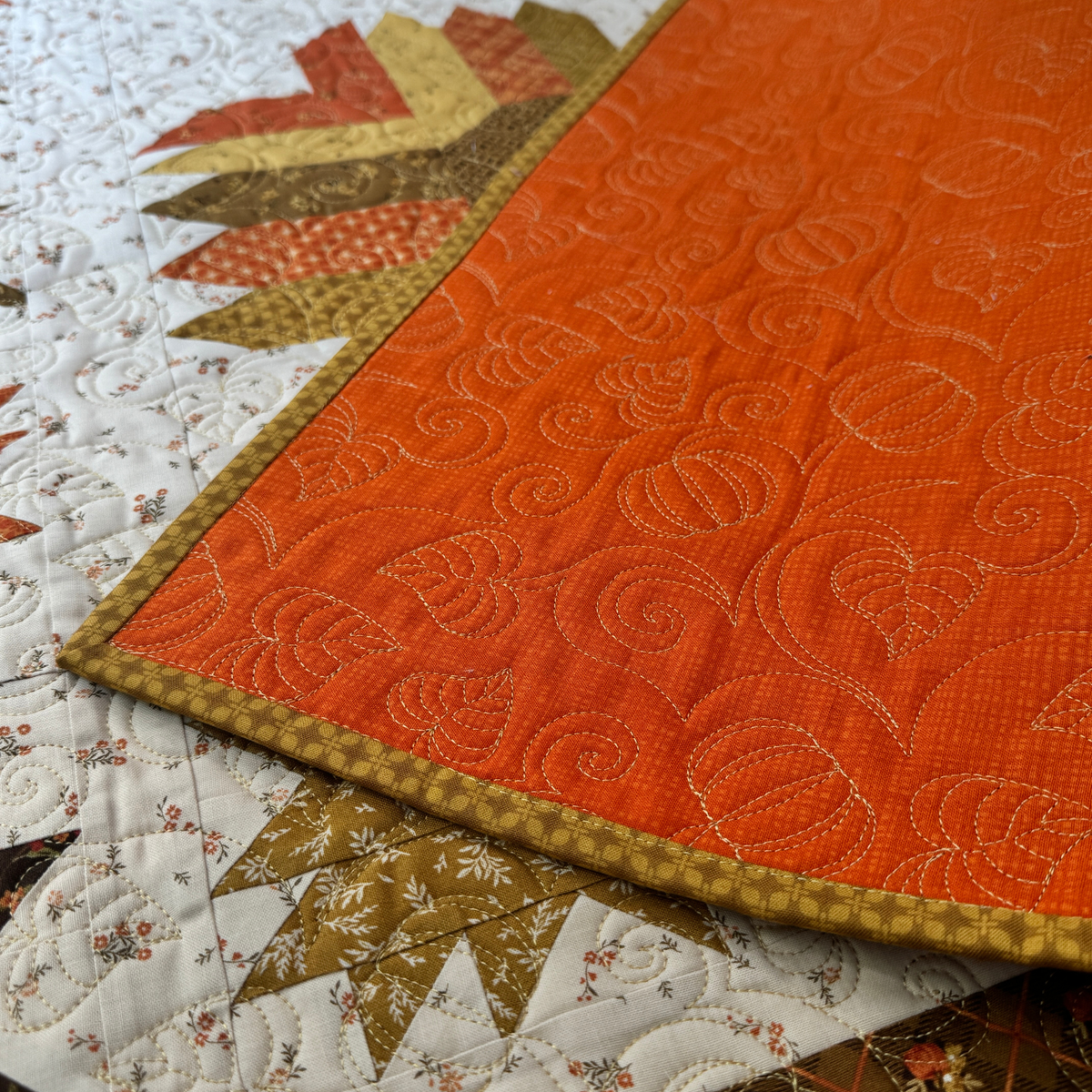 The backing of the finished Autumn Hues quilt requires an additional 1 1/4 yard of Texture fabric in color pumpkin. 