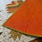 The backing of the finished Autumn Hues quilt requires an additional 1 1/4 yard of Texture fabric in color pumpkin. 