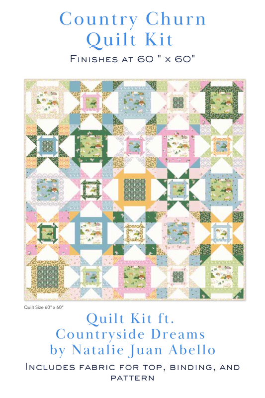 A quilt kit cover featuring a colorful patchwork quilt design with the text 'Country Churn Quilt Kit' and 'Quilt Kit ft. Countryside Dreams by Natalie Juan Abello' on a white background.