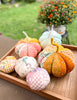 Decorative fabric pumpkins on a wooden tray with a garden background