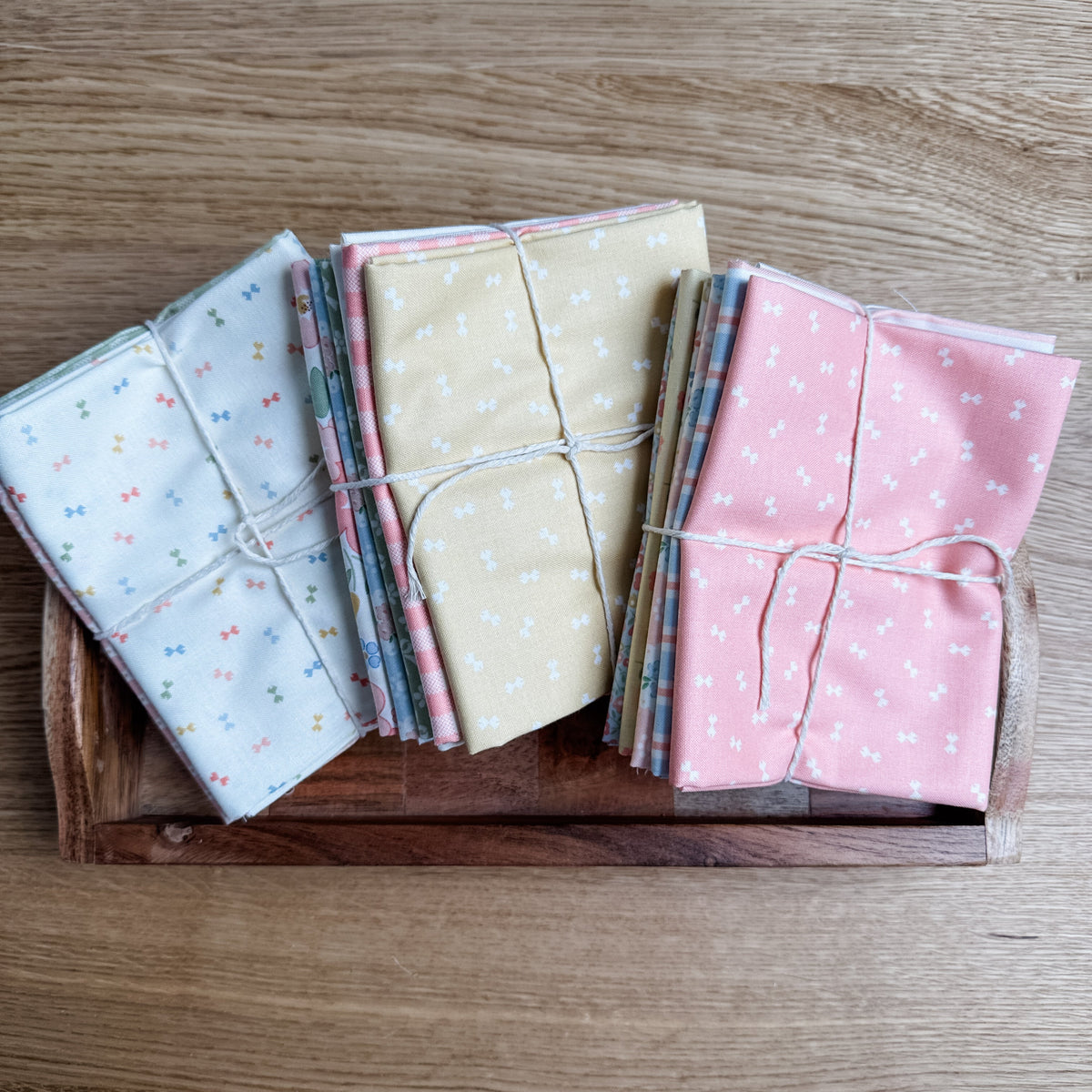 Handmade Sweetness by My Sew Quilty Life for Moda Fabrics petite fat quarter bundles in Multi, Peach, and Butterscotch, tied and displayed side by side on a tray.