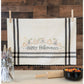 An off-white cotton kitchen towel with black stripes and a 'Happy Halloween' pumpkin embroidery, hanging from a string with wooden clothespins on a rustic wood-paneled wall.