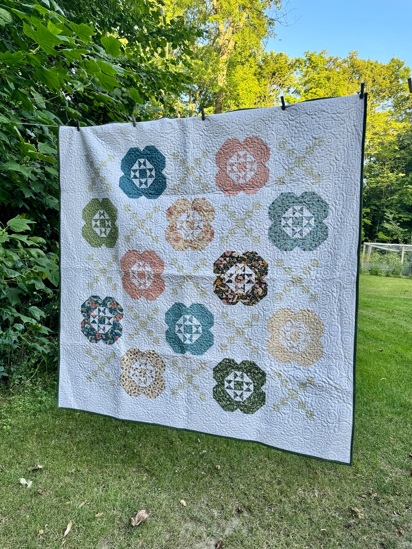 Gardenia Quilt hanging outside.  Features 12 flower blocks and 13 Irish chain blocks alternating.  Made using Petalush fabrics. 