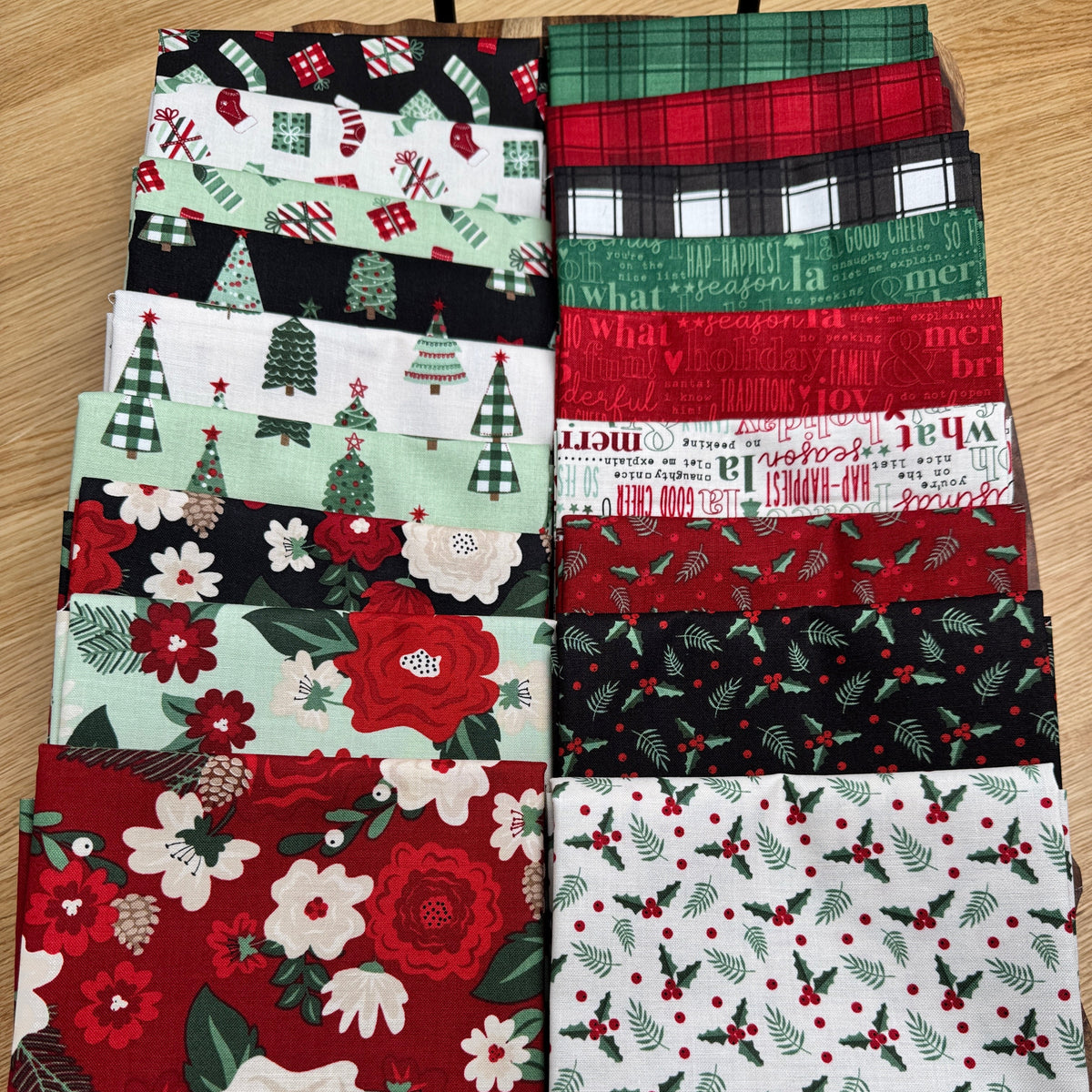 Evergreen Wishes fat quarters spread out on a tray showing the variety of Christmas prints