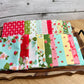 20 Piece fat quarters on a wooden tray.  Bloomsberry fabrics in red, teal, yellow, green, and whites with strawberry and floral motifs.  