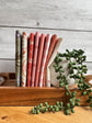 Rosemary Hedgerow Haven petite fat quarter bundle standing on end on a wooden tray next to a plant