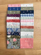 Hedgerow Haven fat quarter bundle standing on end on a wooden tray next to a plant, shop-cut by Treeline Quilting