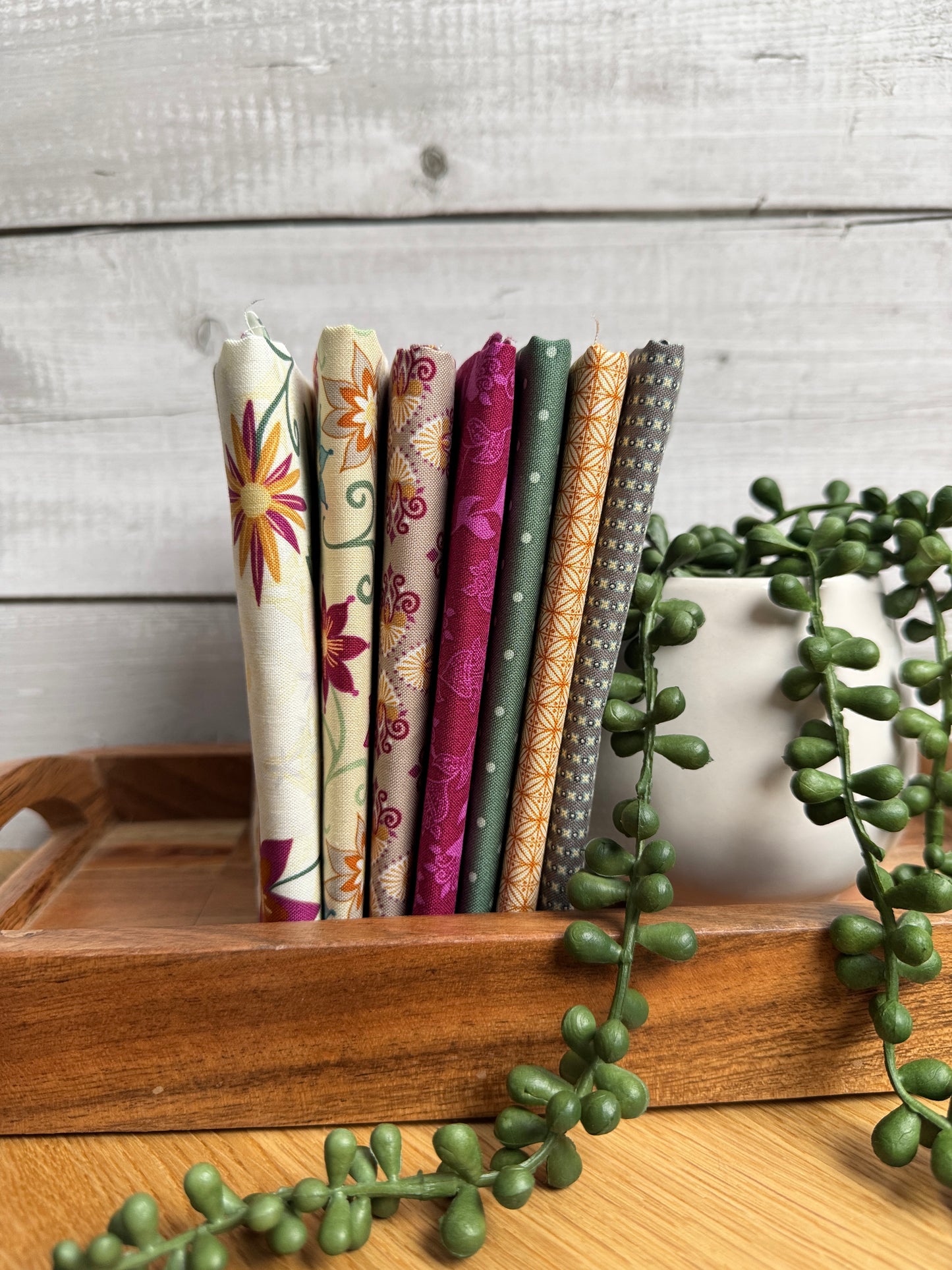 Cream Where the Wild Flowers Are petite fat quarter bundle standing on end on a wooden tray next to a plant