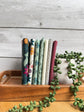 Dark Teal Where the Wild Flowers Are petite fat quarter bundle standing on end on a wooden tray next to a plant
