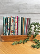 Where the Wild Flowers Are fat quarter bundle standing on end on a wooden tray next to a plant, shop-cut by Treeline Quilting