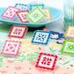 Colorful square-shaped clips with various patterns on a table.