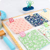 Colorful fabric samples with floral patterns on a white surface, surrounded by sewing tools.