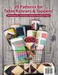 Tabletastic! back cover.  A quilted table runner and topper bundle displayed in a wire basket against a rustic whitewashed wood background. Large red text at the top reads '20 Patterns for Table Runners & Toppers!' with smaller supporting text about colorways and precuts/scraps.