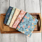 5 piece fat quarter bundle of Petals and Hazel collection on a wooden tray.  