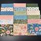 A 4x4 grid of 16 folded fabric swatches from the Petalush fabric collection by Kiley's Quilt Room for Moda with various floral and botanical patterns in pastel and earthy tones, arranged on a dark background.