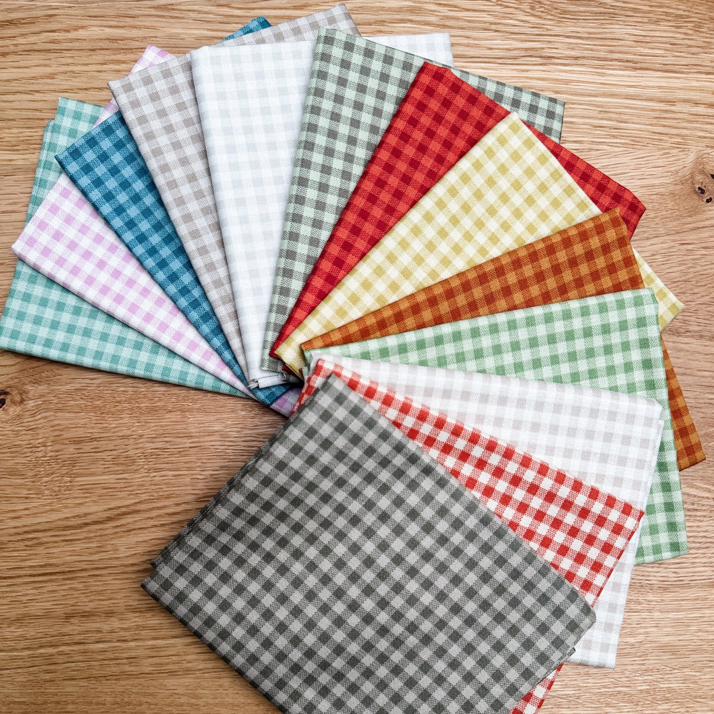 Thirteen Quiltessential Minis check fat quarters by Laundry Basket Quilts, fanned out to show the fabrics.