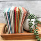 Thirteen Quiltessential Minis check fat quarters standing on end on a tray beside an artificial plant.