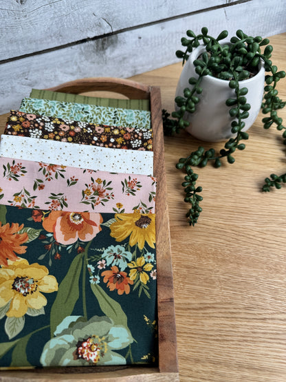 Stylized photo of 6 fat quarters from Worth Repeating fabric collection with the dark green main print .  