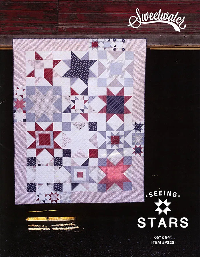 A quilted patchwork textile displayed flat against a dark background, featuring star and geometric block patterns in white, light blue, navy, and red. The image includes visible branding text reading 'Sweetwater' at the top right and 'Seeing Stars' with size and item number at the bottom right.